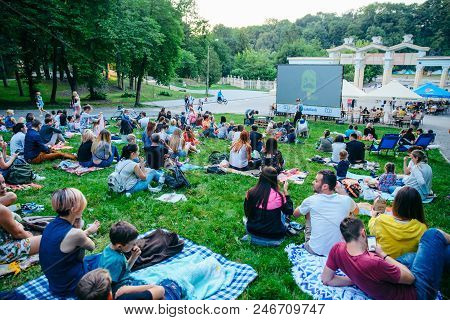 Lviv, Ukraine - June 1, 2018: People Sitting On Grass In City Park Watching Movie In Open Air Cinema