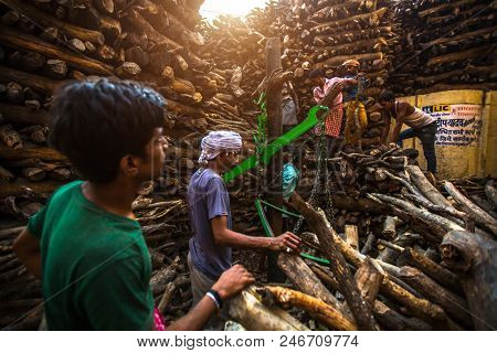 VARANASI, INDIA - MAR 22, 2018: Locals near Holy Ganges weighed for sale wood for cremation. Manikarnika Ghat is one of the ghats in Varanasi and is most known for being a place of Hindu cremation.