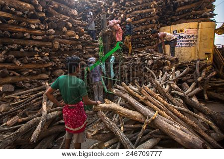 VARANASI, INDIA - MAR 22, 2018: Locals near Holy Ganges weighed for sale wood for cremation. Manikarnika Ghat is one of the ghats in Varanasi and is most known for being a place of Hindu cremation.