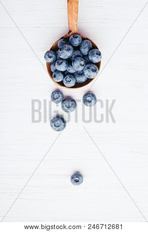 Ripe Bluberries In Wooden Spoon On White Wooden Table. Top View.