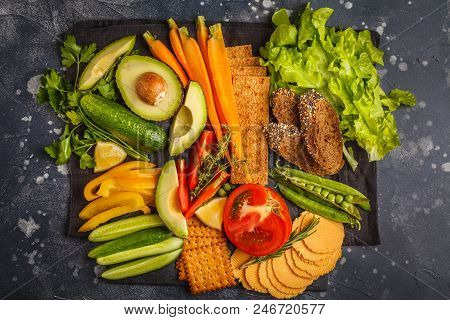 Vegetarian Different Snacks And Fresh Vegetables On A Dark Background. Healthy Vegan Food Concept.