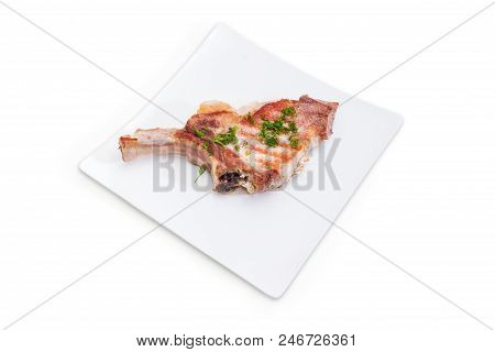 Grilled Pork Loin Chop With Partly Frenched Rib And Sprinkled With Chopped Dill On White Square Dish