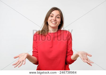 Young Woman In Red Sweater Standing Disorientated Bewildered Isolated On Gray Wall Background. Decis