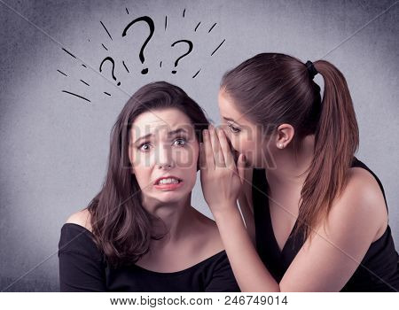 A teenager girl looking confused with drawn question marks above the head, while a girlfriend whispers something in her ear concept.