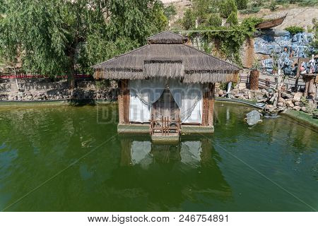 Small House Or Tea Room On A Lake With Trees On Background.