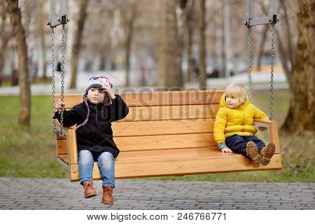 Kids Have Fun On The Swing. Little Boy And Girl On Kindergarten Back Yard. Spring/summer/autumn Outd