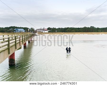 Prerow Germany - January 25 2018: Two Winter Scuba Divers Walking With Their Gear In Shallow Water T