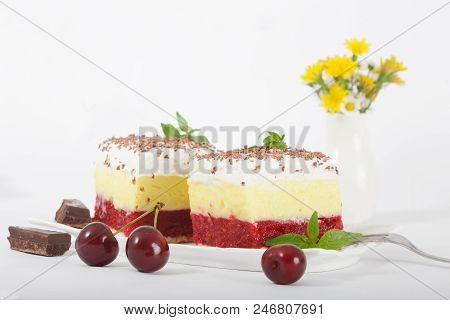 Sweet Homemade Cherry Cake With Vanilla And Whipping Cream On White Plate. Small Vase With Wild Flow
