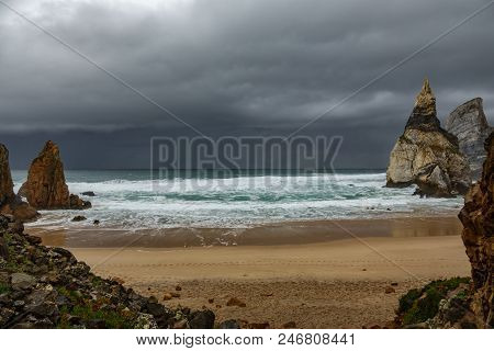 Praia Da Ursa Beach And Rock Formations Under Stormy Clouds