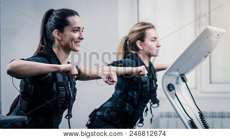 Young Athletic Women In Ems Suits Exercising In Modern Gym