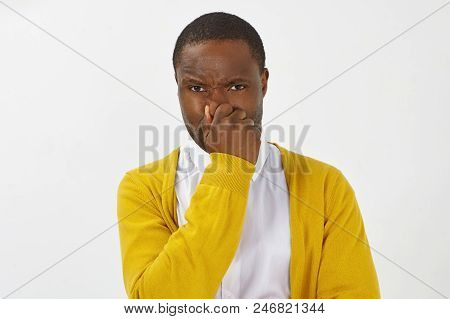 Displeased Frustrated Dark Skinned Man In Stylish Yellow Cardigan Holding Breath And Pinching Nose B