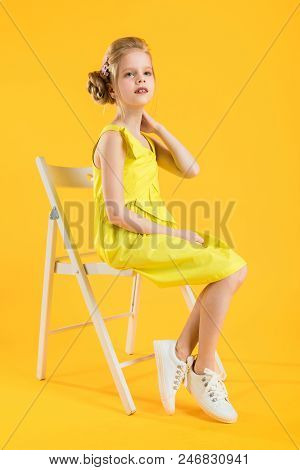 Portrait Of A Teenage Girl In A Yellow Dress. At The Child Hair Are Collected In A Fascicle And Are 