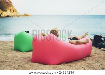 Young Hipster Relaxing On Coastline Beach On Inflatable Lazy Air Pouffe Sofa, Person Tourist Enjoy S