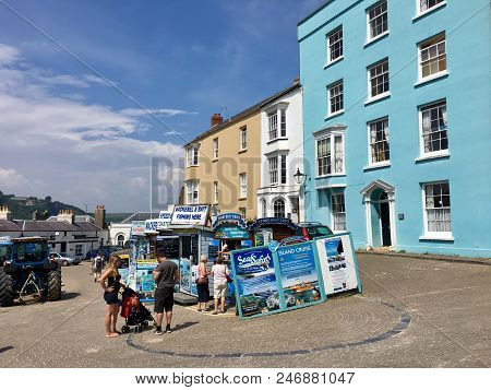 Tenby, Uk: June 10, 2018: Tourists Look At The Boards Advertising The Price And Times Of Fishing Or 