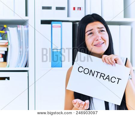 Young Unhappy Female Office Worker Ripping Contract At The Desk.