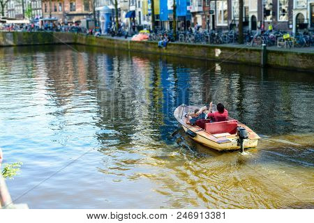 Two Persons Floating On The Boat On The River Amstel In Amsterdam, The Netherlands