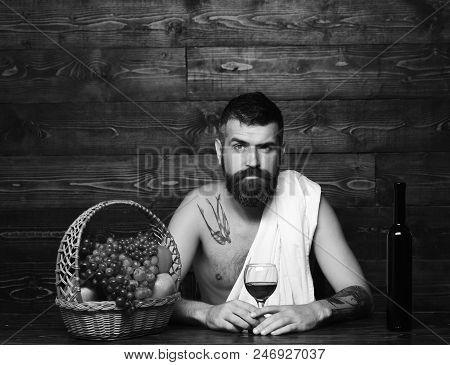 Viticulture And Autumn Harvest Concept. Man With Beard Holds Glass Of Wine On Vintage Wooden Backgro