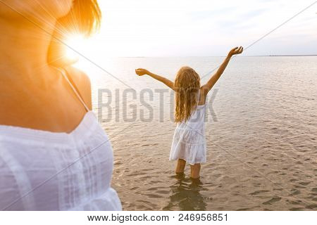 Happy Weekend By The Sea - Mom And Daughter In White Dresses Walking By The Sea At Sunset. Ukrainian