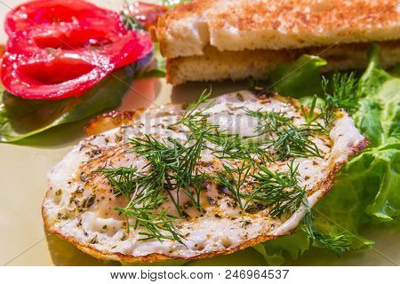 Breakfast Of Fried Eggs With Fresh Tomatoes, Lettuce And Hot Toast