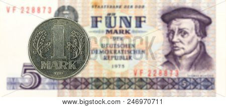 1 Mark Coin Against Historic 5 East German Mark Bank Note