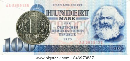 1 Pfennig Coin Against Historic 100 East German Mark Bank Note