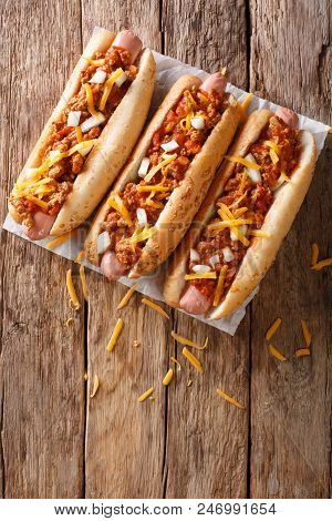 Traditional American Chili Hot Dogs With Cheddar Cheese, Onion And Spicy Sauce Closeup. Vertical Top