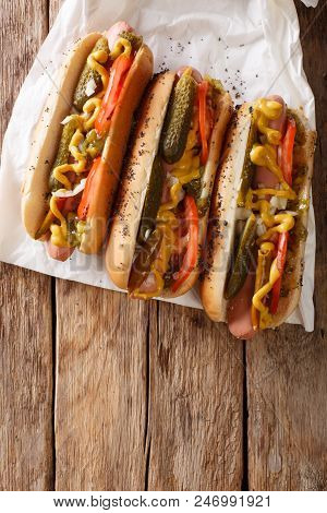 Chicago Style Hot Dog With Mustard, Tomatoes, Pickled Cucumbers, Onions And Sauce Close-up. Vertical