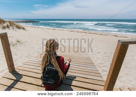 Blonde girl with the dreads is on the path to the ocean.