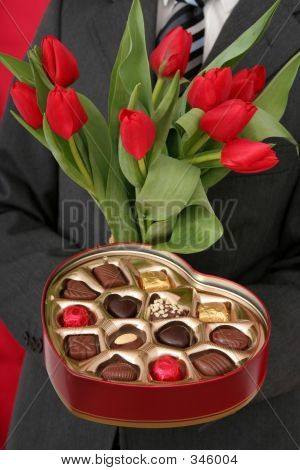 Muž, který držel ve tvaru srdce Box Candy a červené tulipány
