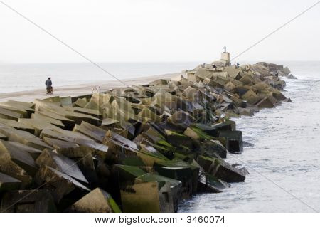 Pescadores e caminhantes no quebra-mar