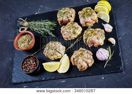 Raw Rabbit Ballotine Prepared To Be Cooked On A Black Slate Plate With Herbs And Spices, Horizontal 