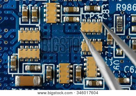 Installing Or Removing Electronic Components On A Blue Electronic Board With Forceps, Soldering, Mac