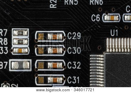 Black Computer Video Card Board With Brown Microcircuits And Various Electronic Components, Top View
