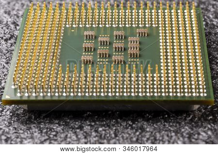 Old Computer Processor With Gold-plated Legs, Microcircuits On It, On A Black Soft Substrate Close-u