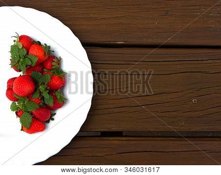 Strawberries On A White Plate On A Wooden Table