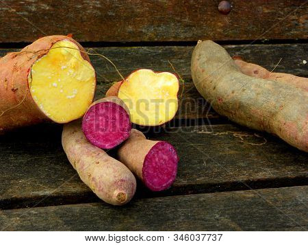 Red And Yellow Sweet Potatoes On A Wooden Table
