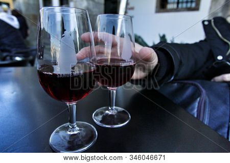 Porto, Portugal- December 30, 2019: Hand Catching A Glasse Of Tasty Port Wine Tawny Sandeman Brand O