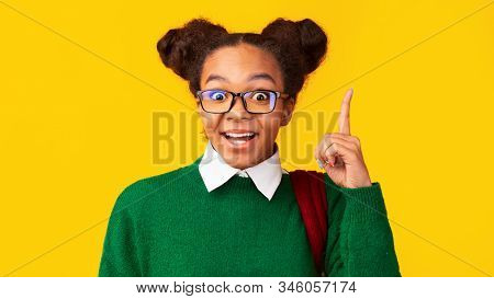 Aha Moment. Headshot Of Excited Black Girl With Opened Mouth Pointing Finger Up At Studio, Copyspace