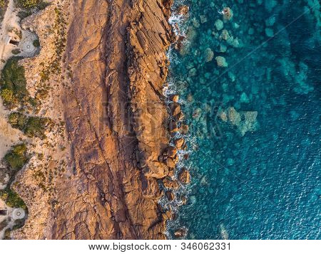 Above Aerial View Of Rocky Shore Of Sardinia Island In Mediterranean Sea. Waves Crash Against Rocks 