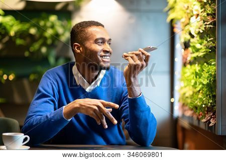 Voice Search. Happy Black Man Using Voice Assistant On Mobile Phone Or Calling On Smartphone At Cafe