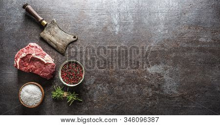 Raw Beef Steaks With Meat Cleaver And Salt Pepper On Dark Concrete Background