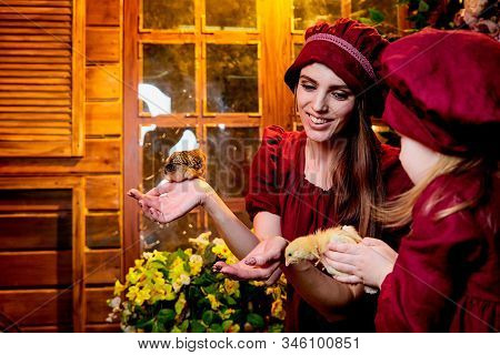 Easter And Family. Mother And Daughter In Maroon Or Red Dresses Of The Village Shepherdesses And Sma