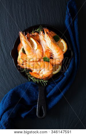 Seafood Concept Ocean King Prawns Cooked In Skillet Iron Cast On Black Slate Stone With Blue Napkins