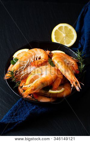 Seafood Concept Ocean King Prawns Cooked In Skillet Iron Cast On Black Slate Stone With Blue Napkins