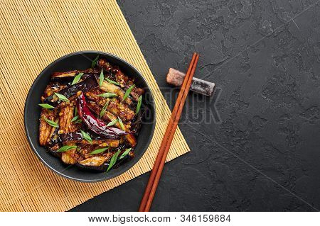 Sichuan Eggplant Stir Fry In Black Bowl At Dark Slate Background. Eggplant Stir Fry Is Chinese Cuisi
