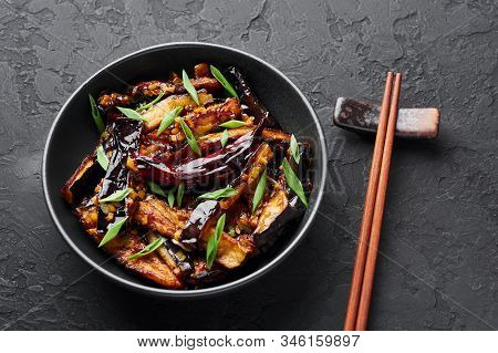 Sichuan Eggplant Stir Fry In Black Bowl At Dark Slate Background. Eggplant Stir Fry Is Chinese Cuisi