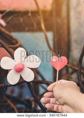 A Red Heart-shaped Candle On Woman's Hand And An Artificial Flower Made Of White And Red Candles Wit