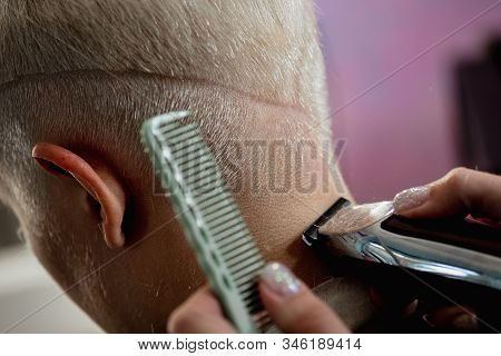 Hairdresser Machine Cuts Woman Client. A Short Haircut, Shaved Temple And A Drawing On The Hair.