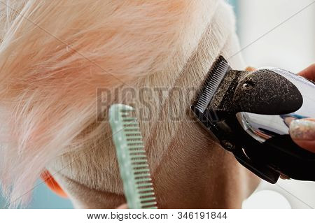 Hairdresser Machine Cuts Woman Client. A Short Haircut, Shaved Temple And A Drawing On The Hair.