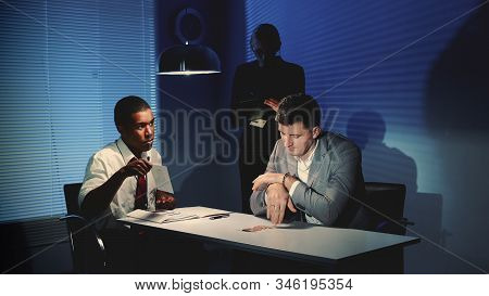 African Police Detective Showing Pictures Of Suspected Robbers Accomplice. In The Background There I